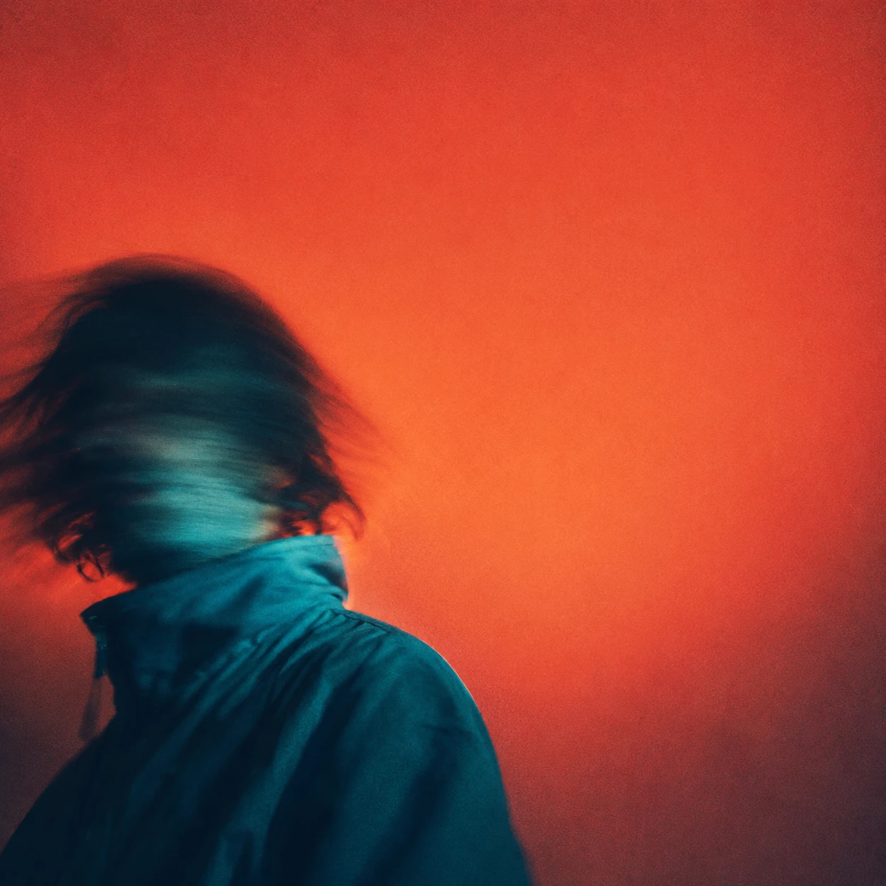 A person in motion blur against an orange wall